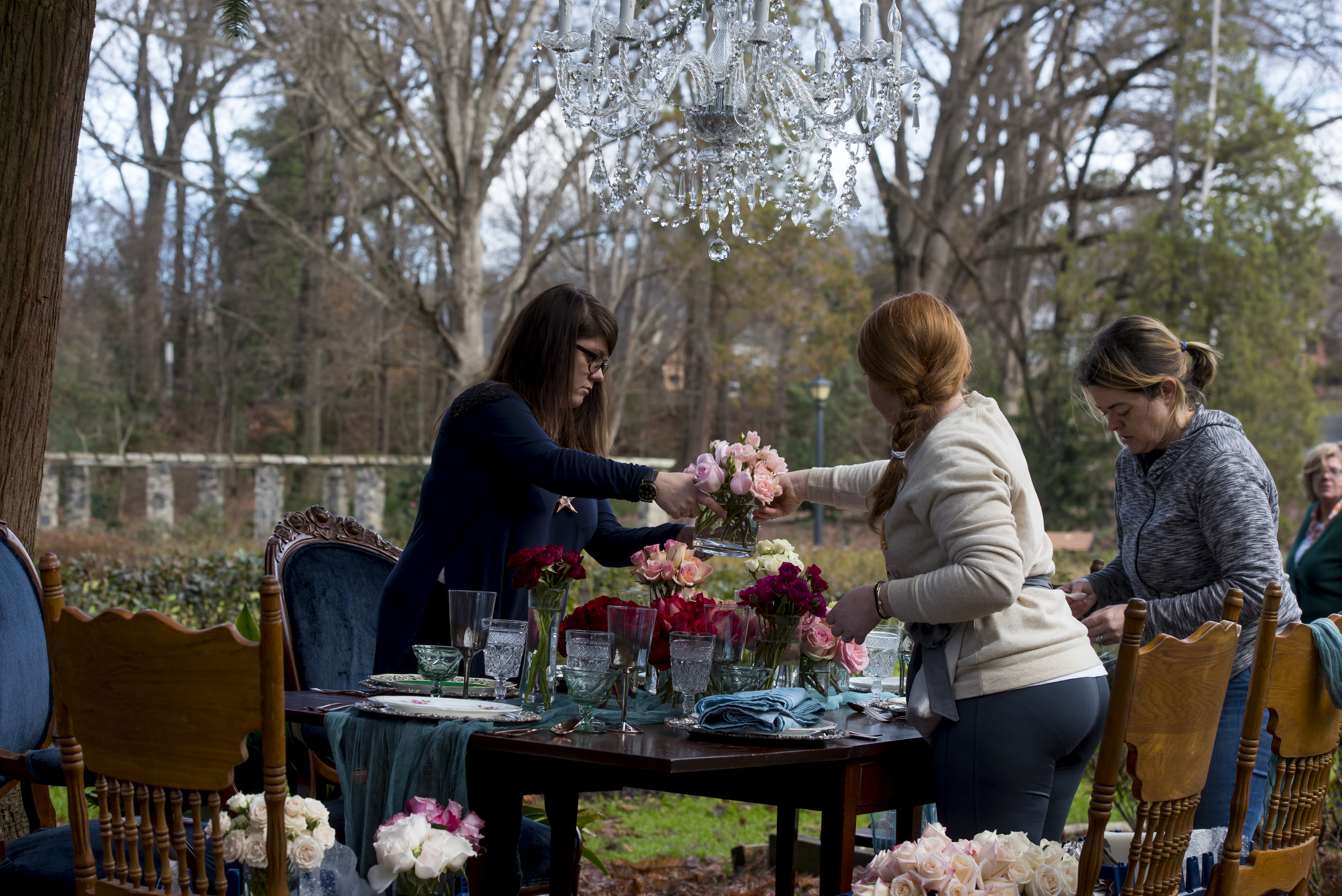 setting up a table with floral centerpieces for a styled shoot